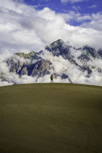 Rear view of man walking on beach against sky