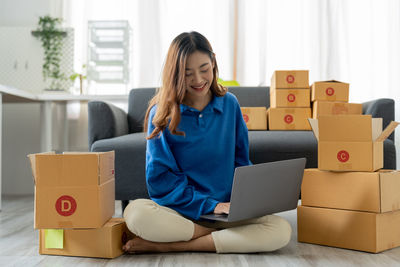 Portrait of young woman using laptop while sitting on sofa at home