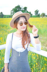 Young woman wearing sunglasses while standing on field