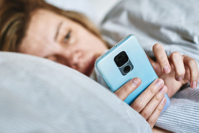 Woman using smartphone in the bed, social media, lazy weekend
