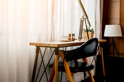 Empty chair and table by curtain at home