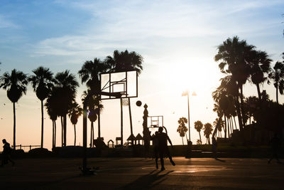 Men playing basketball during sunset