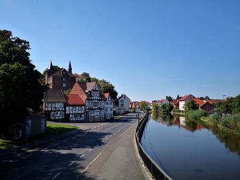 Canal amidst buildings against clear blue sky