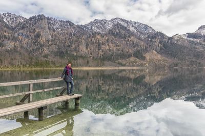 Full length of woman standing on pier over lake against mountains