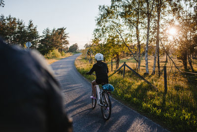 Rear view of people riding bicycle on road