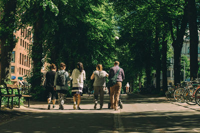 Rear view of people walking on footpath in city