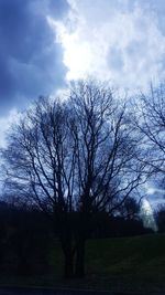 Silhouette bare trees on field against sky