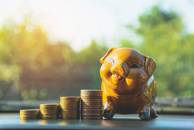 Close-up of stack of coins by piggy bank on car dashboard