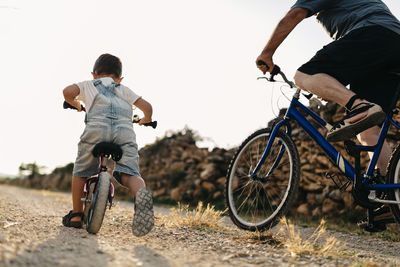 Back view of little boy and his great-grandfather on bicycle tour