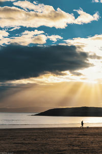 Silhouette person on beach against sky during sunset