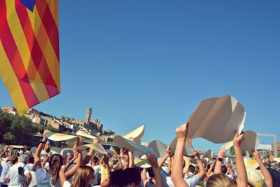 Low angle view of people against clear blue sky