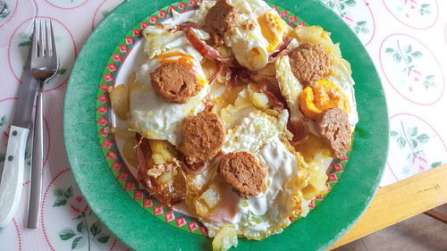 High angle view of scrambled eggs with ham and foie gras served in plate on table