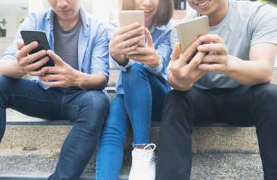 People holding smart phones while sitting on steps