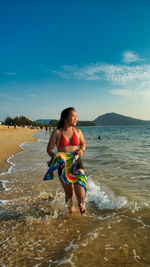 Full length of woman standing at beach against sky