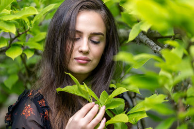 Portrait of young woman holding leaves outdoors