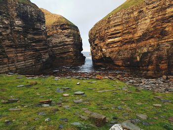 Rock formation on shore against sky