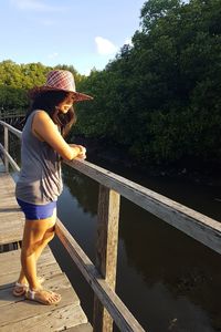 Full length of woman standing on footbridge against lake