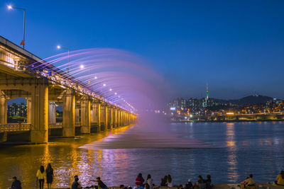 View of illuminated bridge over river at night