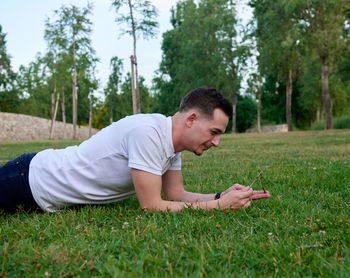 Side view of young man sitting on field