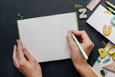 Cropped hands of woman writing on book