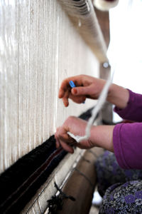 Cropped hands of woman weaving carpet