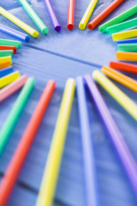 Close-up of colorful straws arranged on blue wooden table