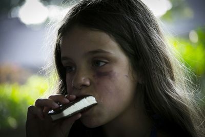 Close-up of girl eating sweet food while looking away outdoors