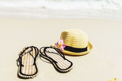 High angle view of flip-flops by sun hat at beach