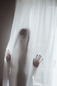 Young woman hiding behind curtain