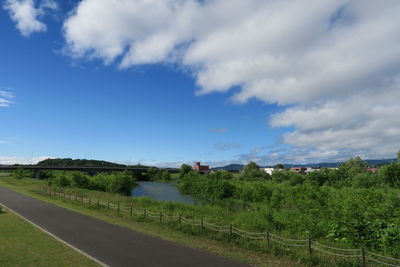 Empty road amidst field against sky