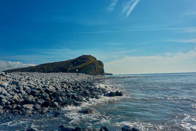 View of rocks on beach against blue sky