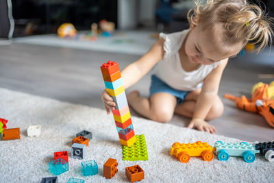 Cute girl playing with multi colored toy at home