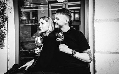 Young man and woman holding glass door