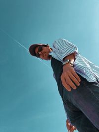 Low angle view of man standing against blue sky