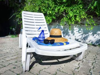 Straw hat, sunglasses, towel and bottle on a white sunbed