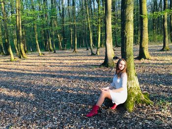 Full length of woman on tree trunk in forest