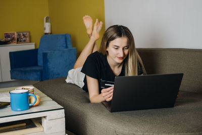 Beautiful woman lying on bed while using laptop at home