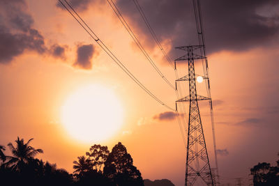 Low angle view of silhouette electricity pylon against sky during sunset