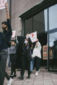 Young male and female protestor with stop racism outside building during pandemic