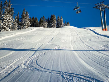 Three single traces at ski slope underneath a chairlift in the austrian alps against blue sky