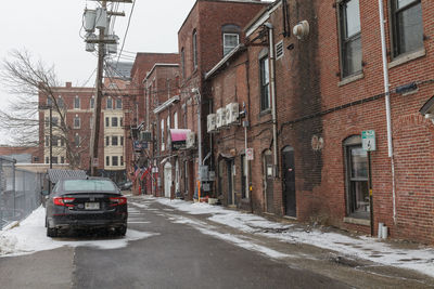 Cars on street by buildings in city during winter
