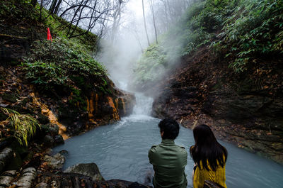 Rear view of friends against waterfall