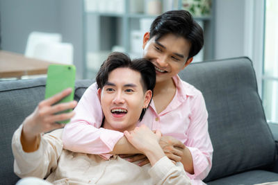 Young woman using phone while sitting on sofa at home