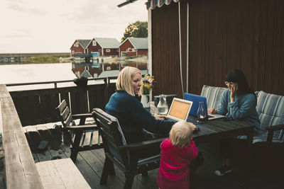 Woman talking to daughter while friend using laptop at table