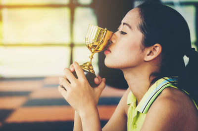 Close-up of young woman kissing trophy