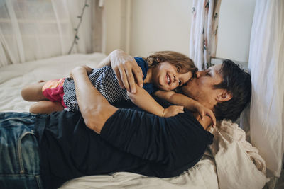 Mature father kissing daughter while lying on bed