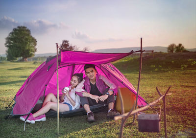 People in tent on grass against sky