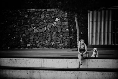 Full length of woman sitting with dog outdoors