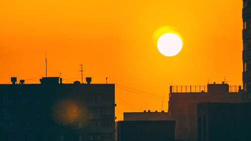 Silhouette buildings against orange sky
