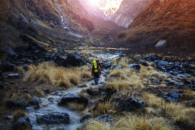 Trekkers carry backpack walking on trail in valley